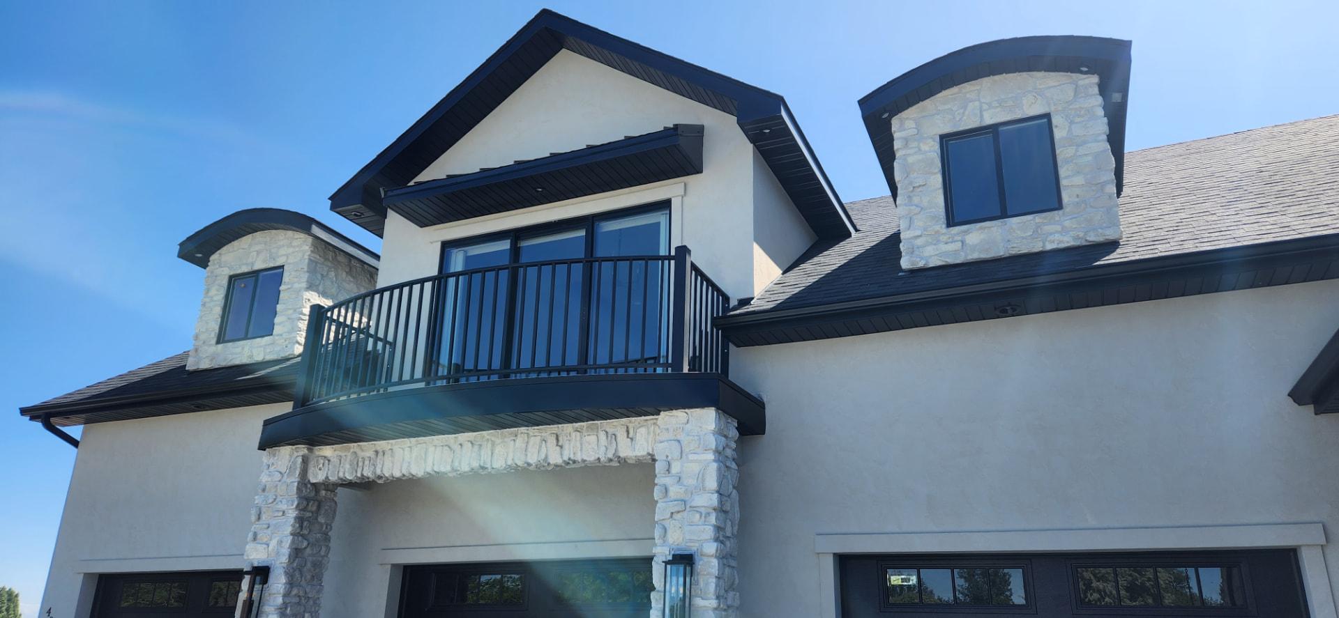 Curved black steel balcony railing on a second story home exterior