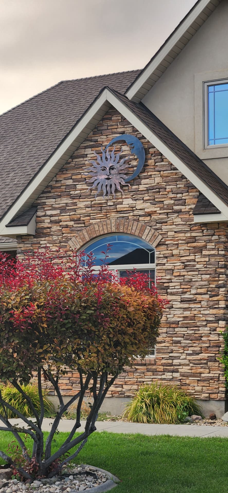 Steel sun and moon wall art mounted on a stone home gable