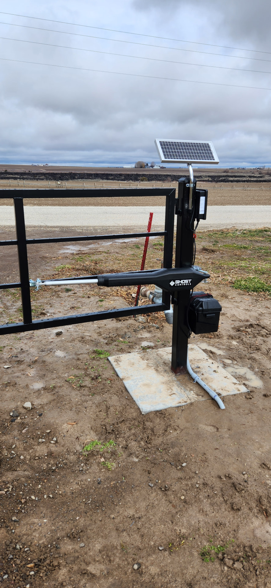 Black steel farm gate with solar-powered automatic gate opener arm