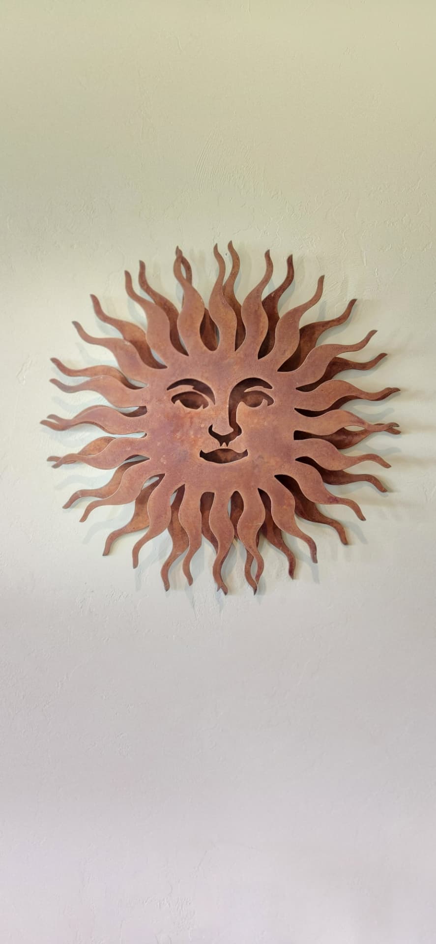 Rust patina plasma cut steel sun face wall art on an interior wall