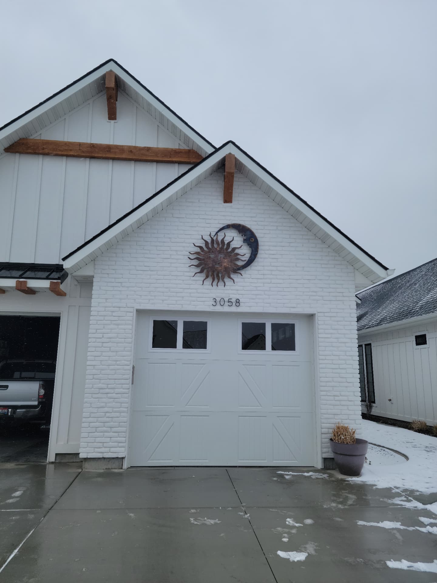 Metal sun and moon wall art mounted above a white brick garage gable