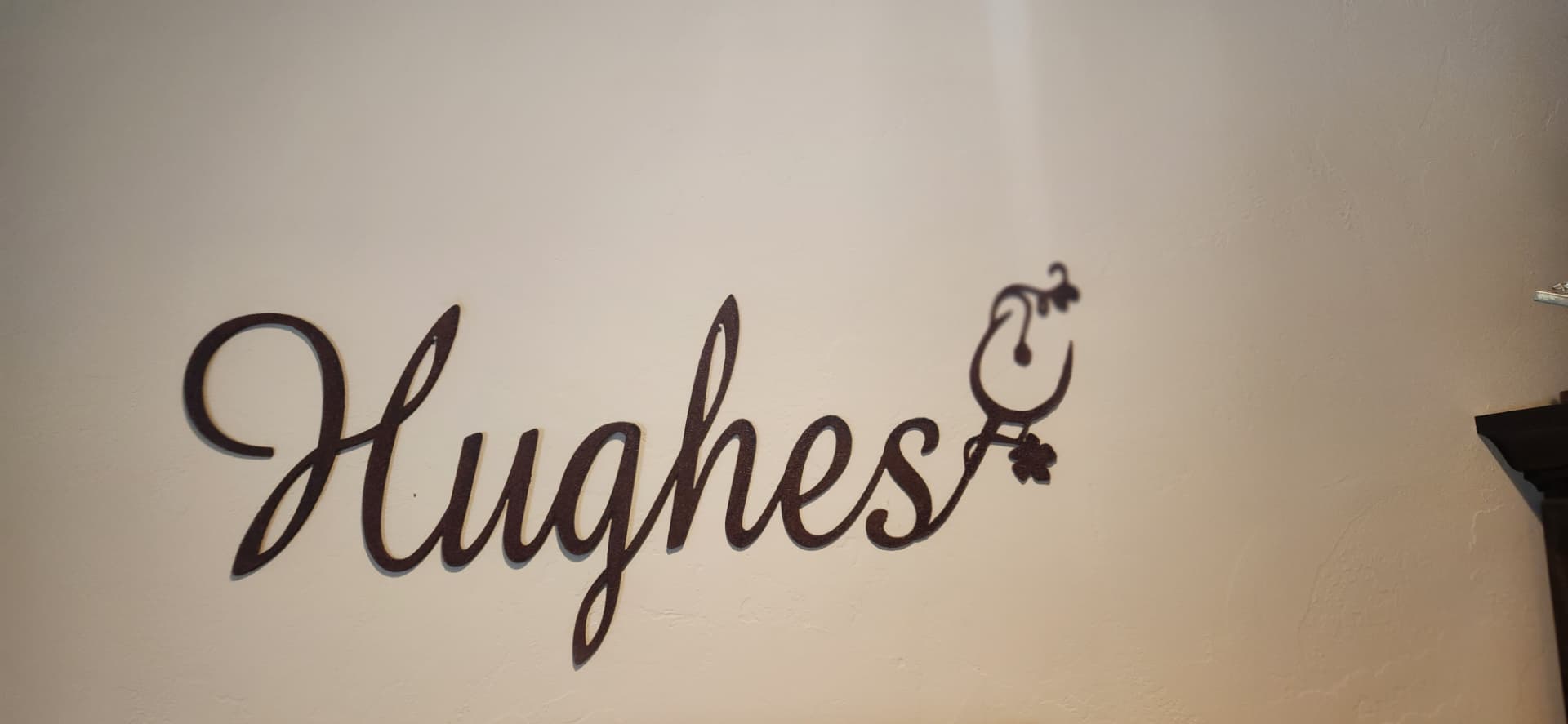 Cut metal script family name sign with wine glass accent on an interior wall