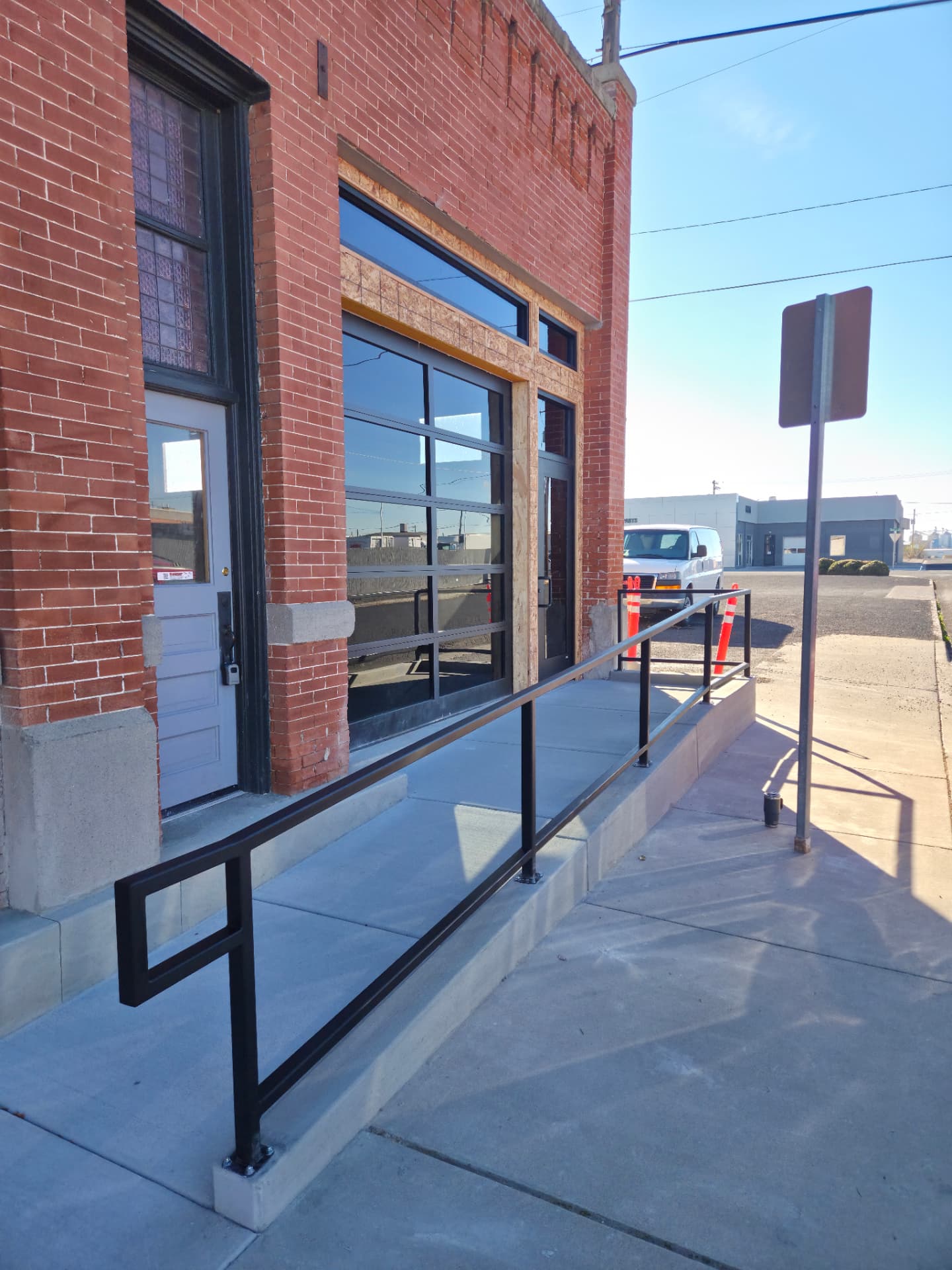Black steel ADA ramp handrail on a downtown brick storefront