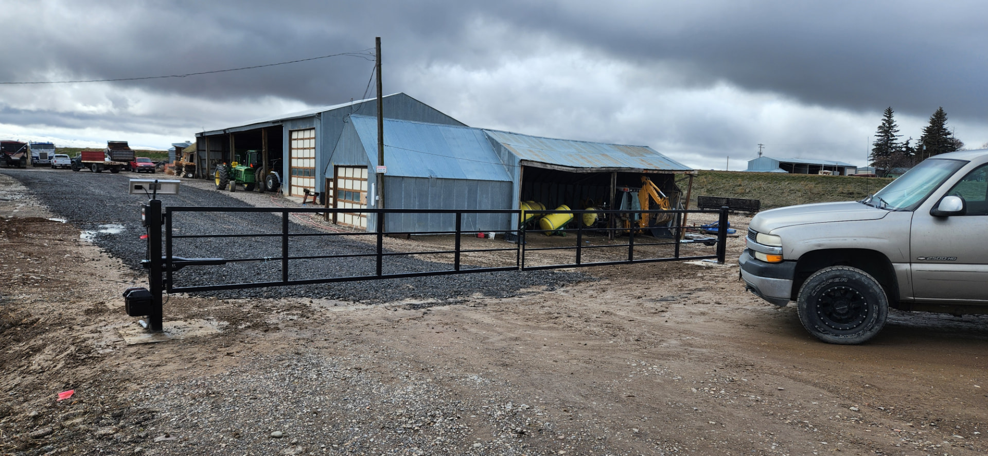 Long black steel ranch gate with automatic opener at a farm entrance