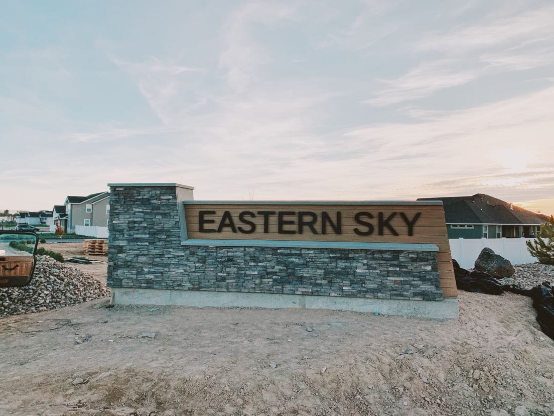 Steel monument letters reading Eastern Sky on a stone and wood subdivision entry sign