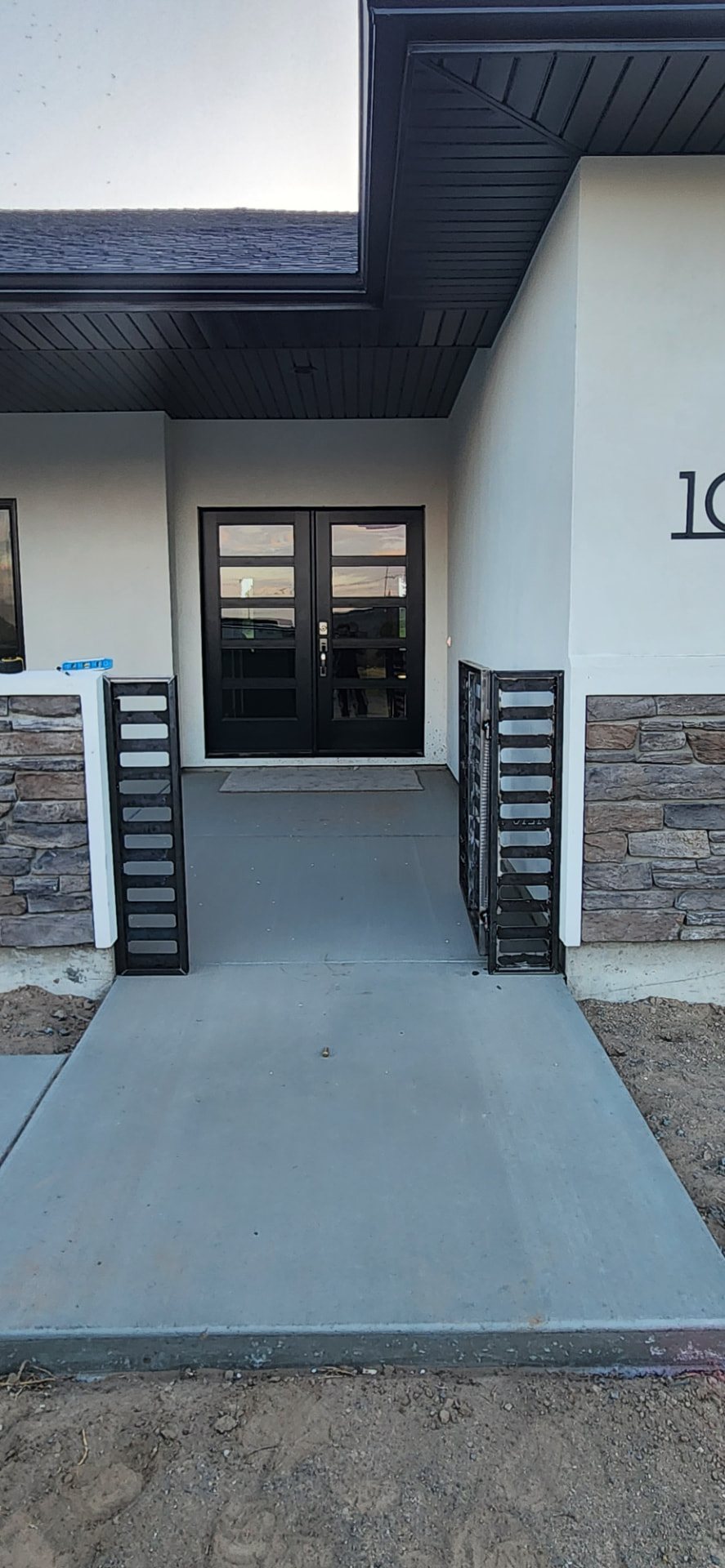 Black steel entry gate panels flanking a modern front door