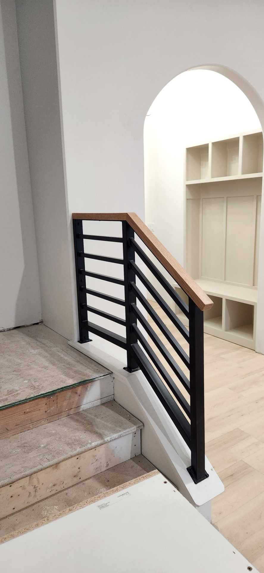 Black steel stair railing with a stained wood top cap