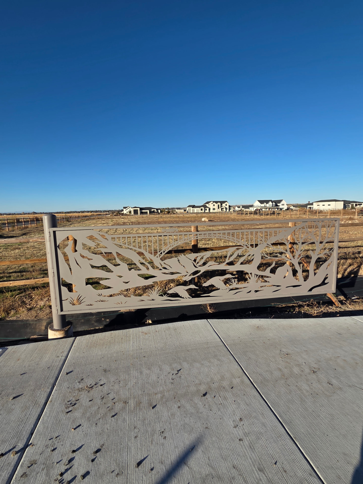 Single steel gate panel with CNC-cut Perrine Bridge, deer, mountains and trees in a rural setting