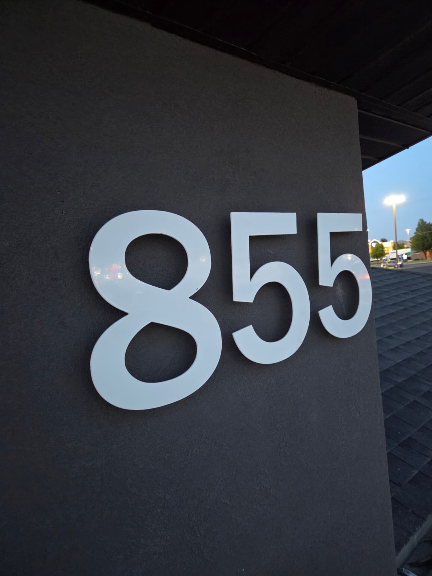 Large white powder coated metal address numbers mounted on a dark stucco wall