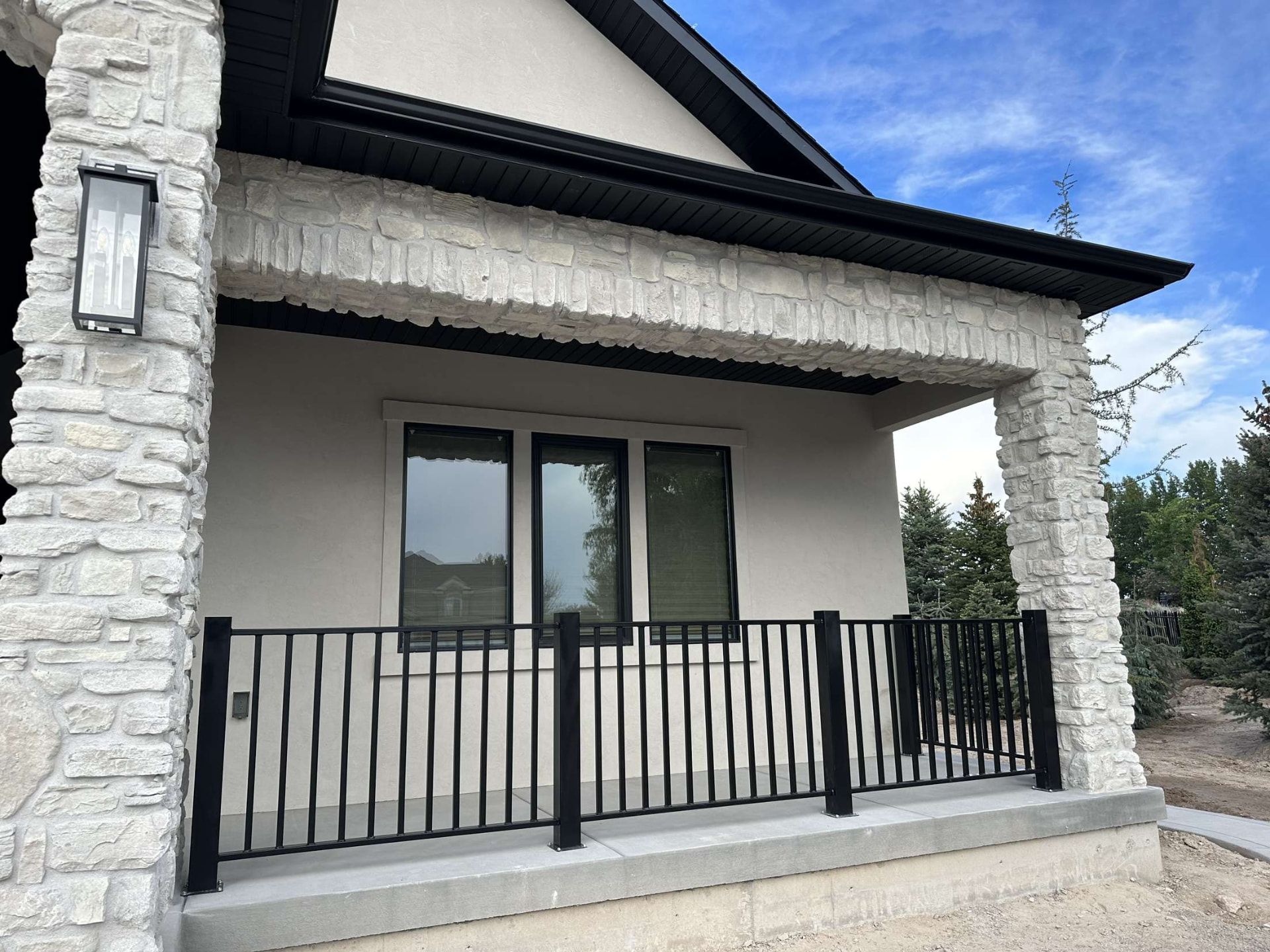 Black steel porch railing on a stucco and stone residential home
