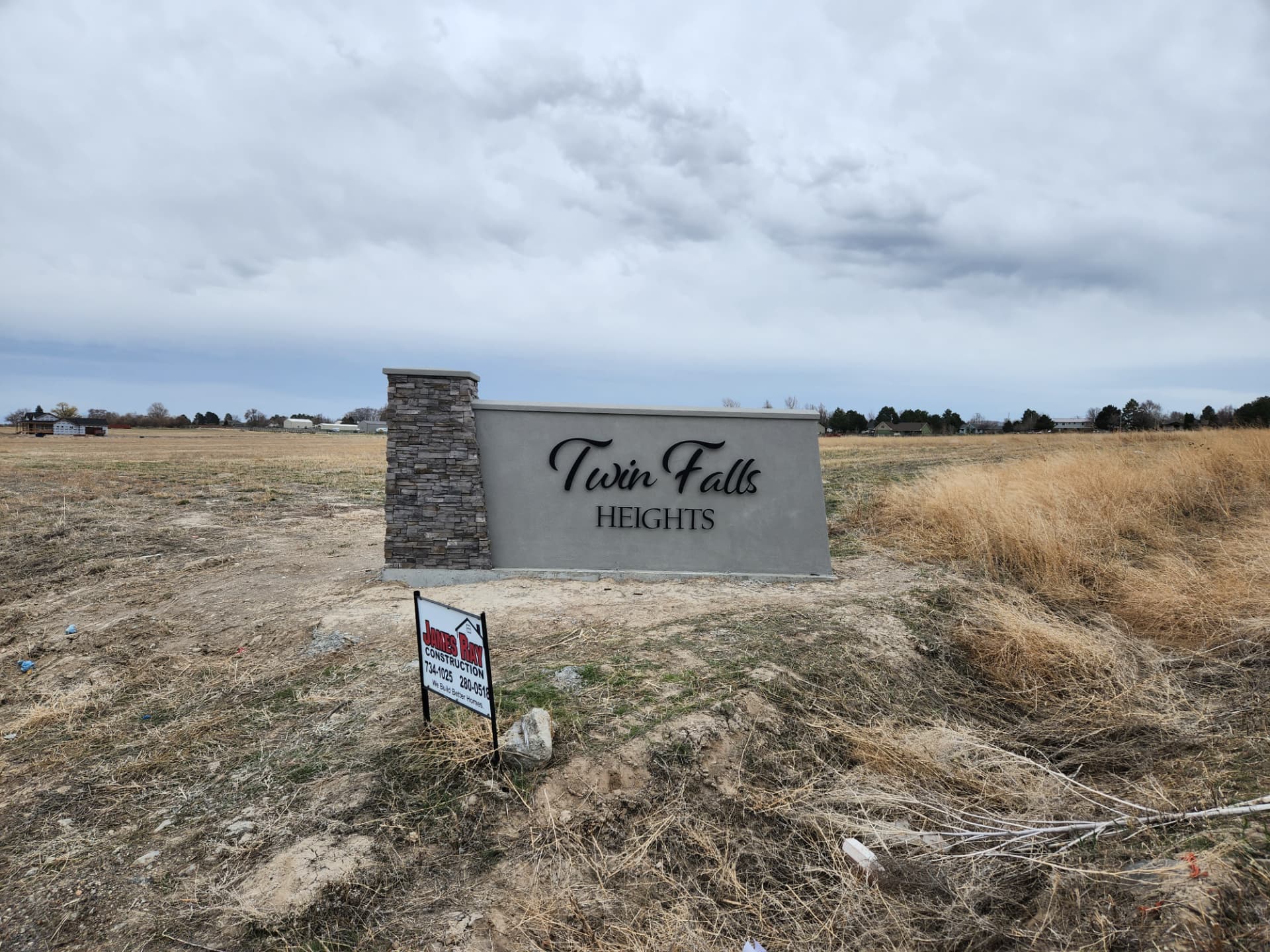 Black cut metal script lettering on a stone and stucco subdivision monument sign