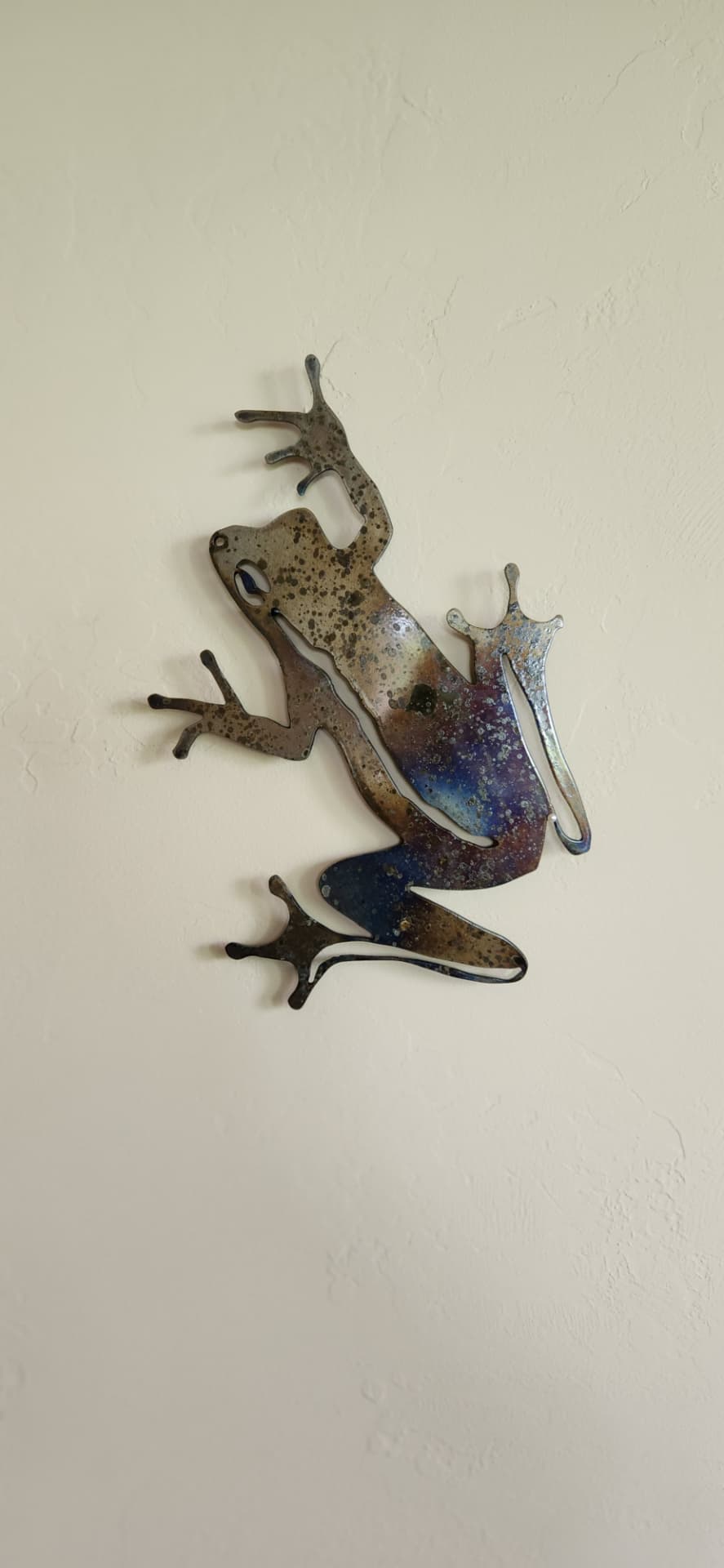 Heat colored steel frog wall art mounted on an interior wall