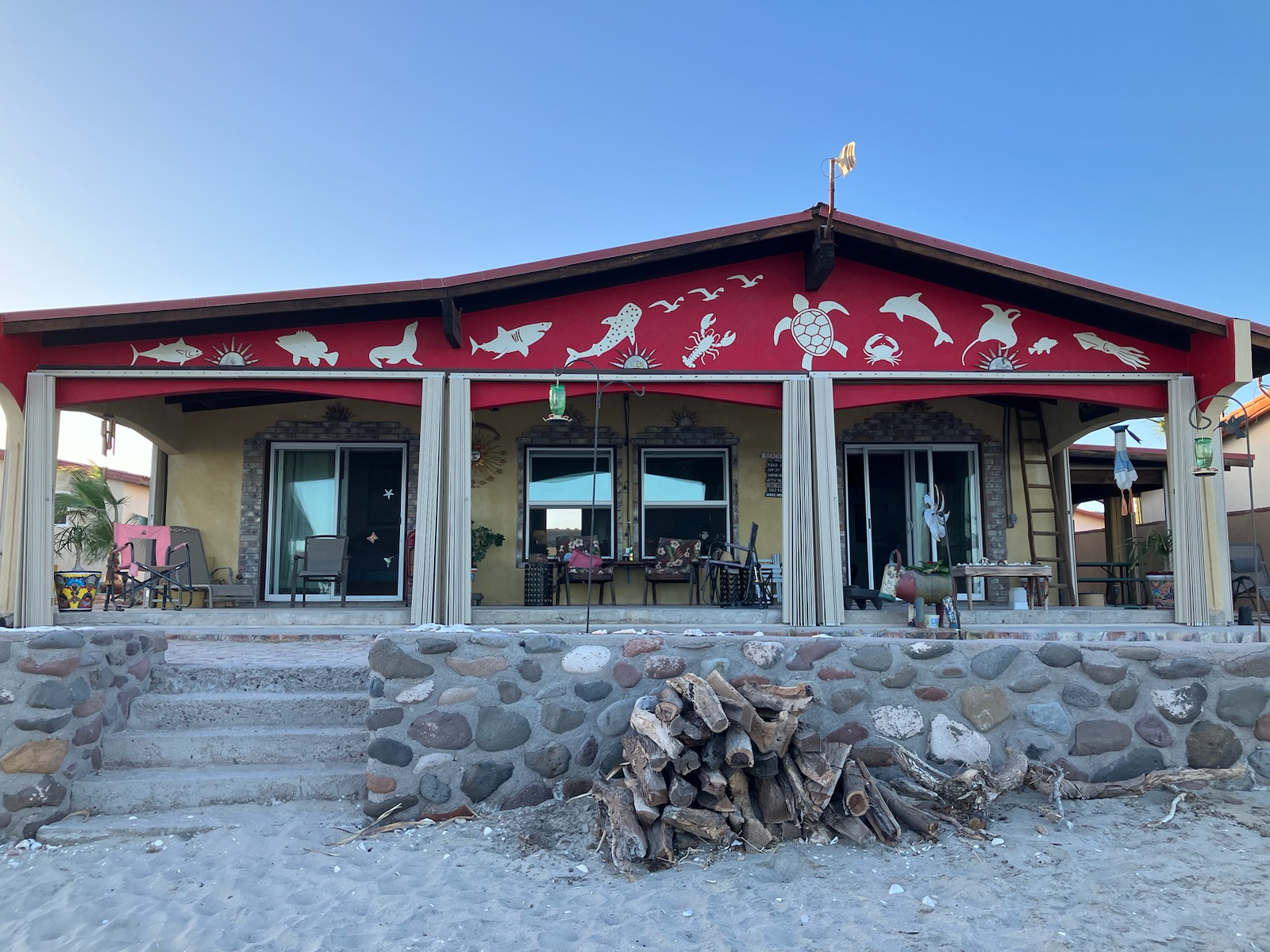 Cut metal sea life silhouettes mounted along a red beach house fascia